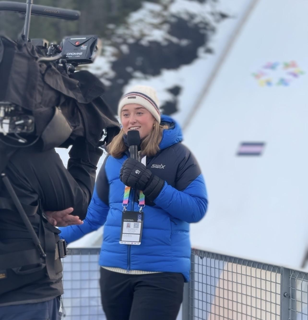 Kvinnelig reporter fremfor hoppbakken i Gran&aring;sen