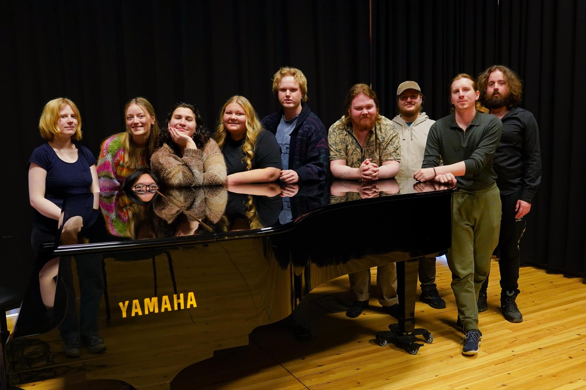 Folk som st&aring;r bak et piano.