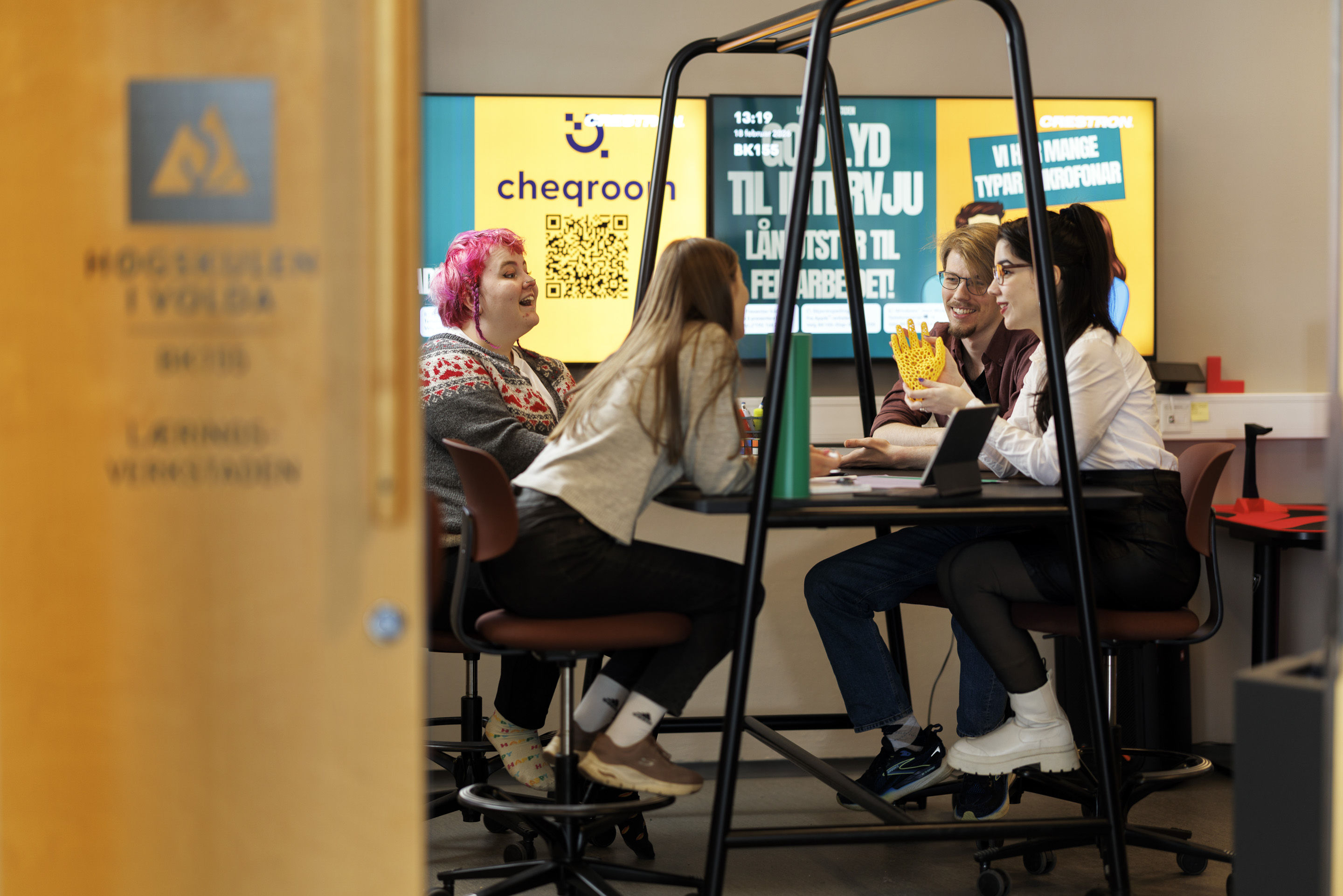 Studentar sit rundt eit bord og snakkar