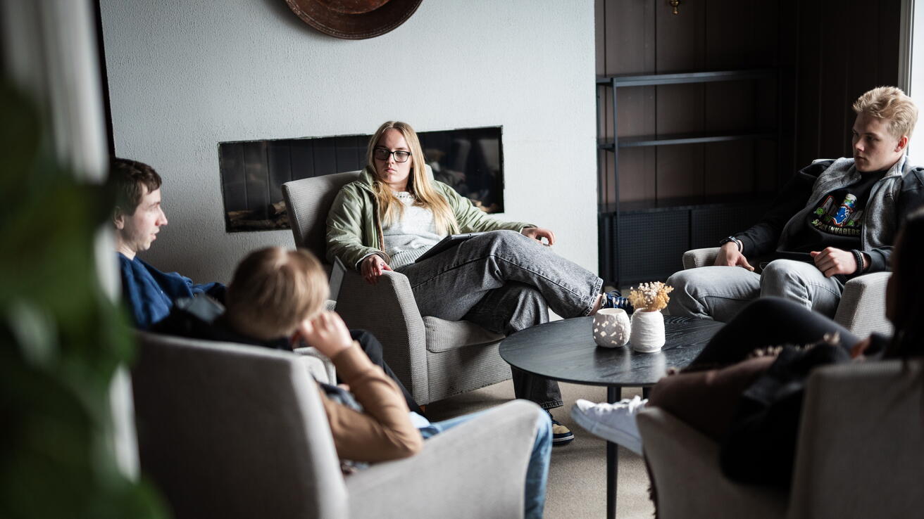 Studenter som sitter rundt et bord og diskuterer i koselige omgivelser